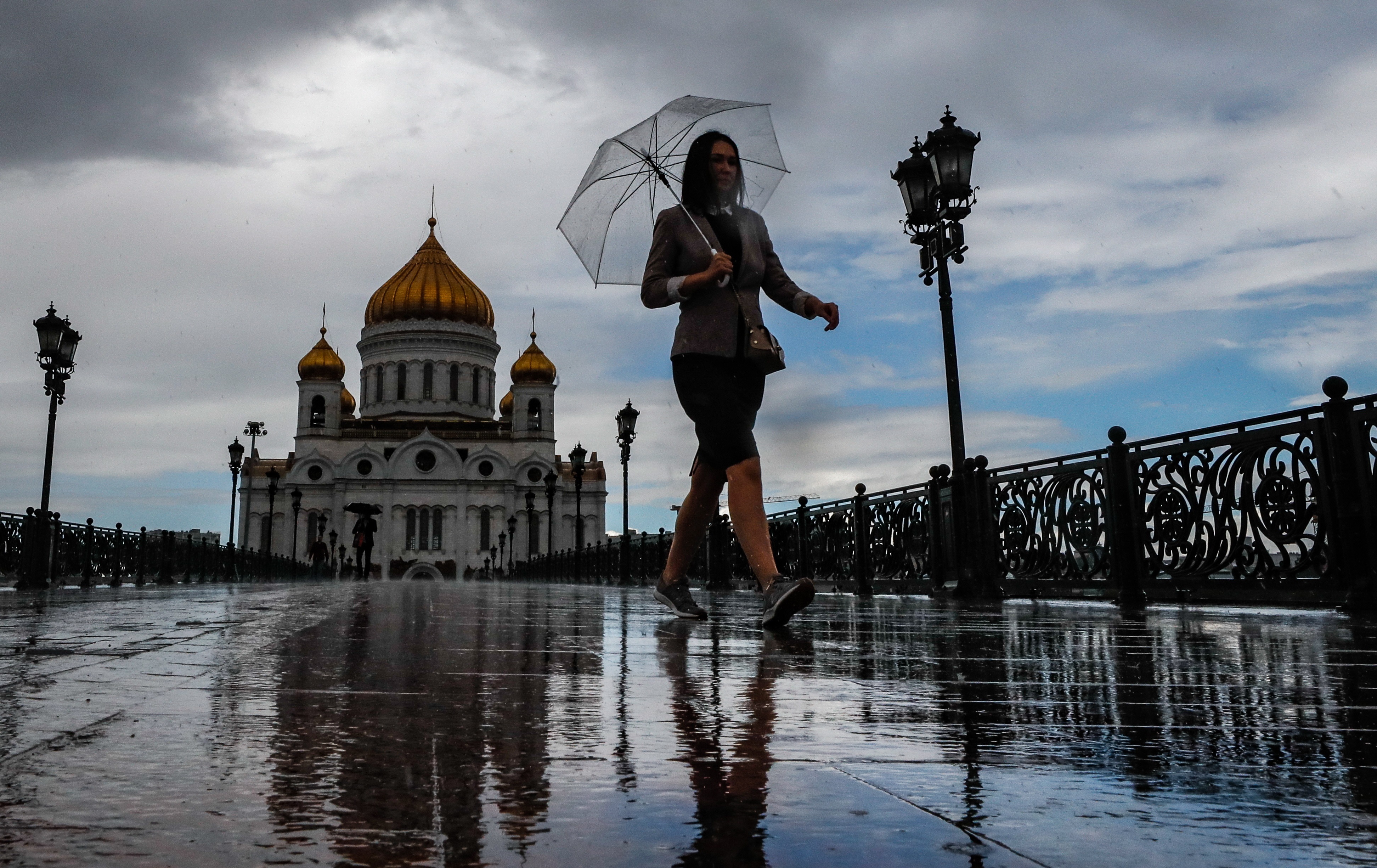 Una mijer camina por un puente bajo la lluvia en Moscú. EFE/EPA/YURI KOCHETKOV